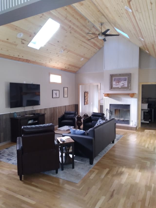 Modern living room with leather furniture, wooden ceiling, and fireplace