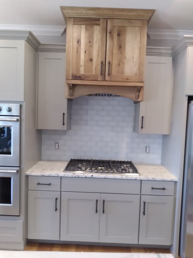 Modern kitchen with marble countertop, gas cooktop, and wooden cabinets