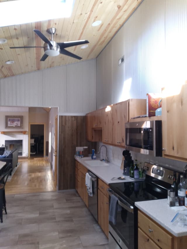 Modern rustic kitchen with wood cabinets, stainless appliances, and vaulted ceiling with a fan