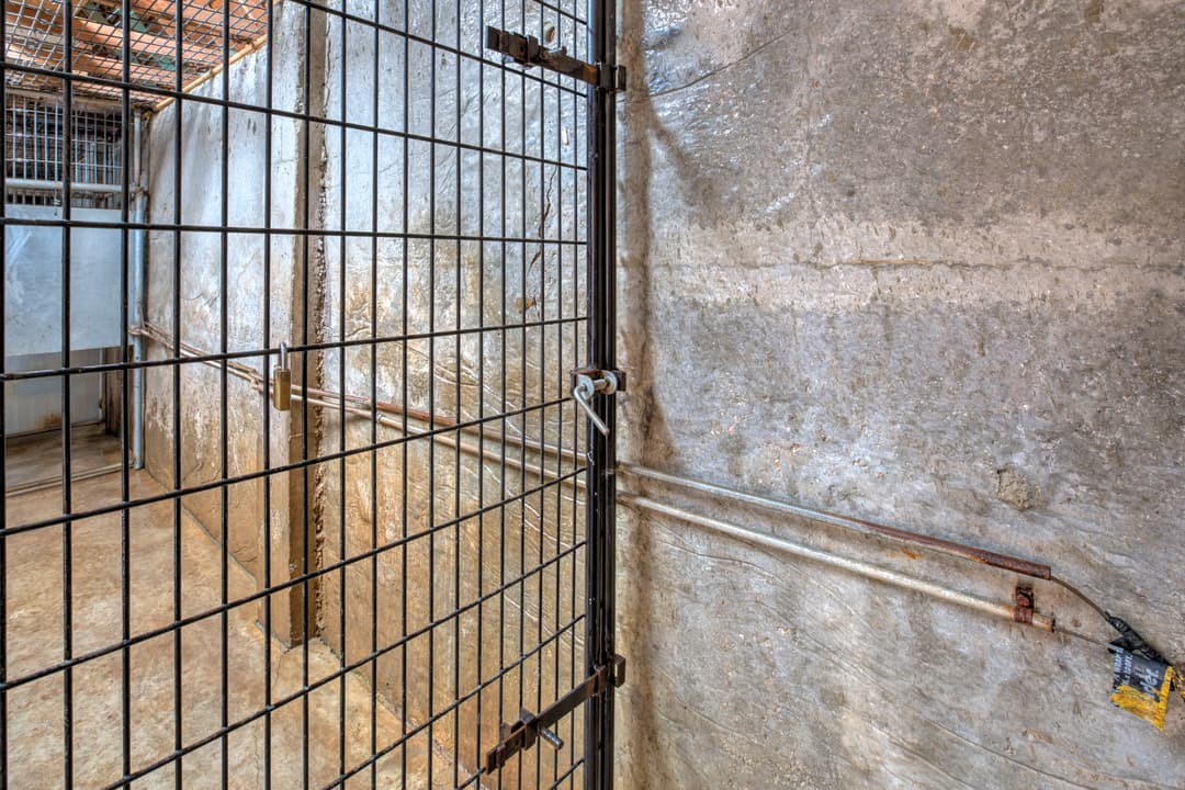 Metal wire storage cage with padlock inside concrete room